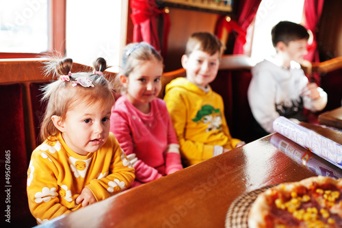 Children on birthdays sitting at the table and eating pizza.