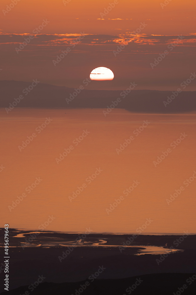 Sunset view of Wales with sun dipping into the coastline 