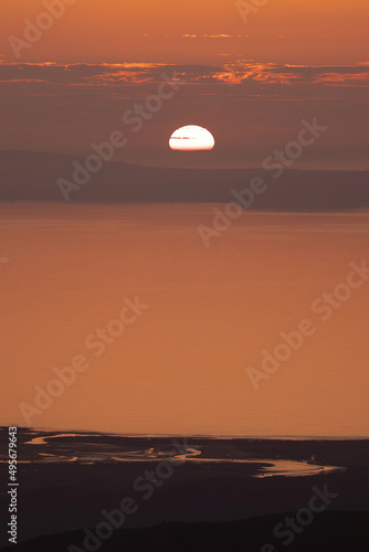 Sunset view of Wales with sun dipping into the coastline 