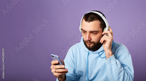 funny bearded man listens music or podcast in white headphones. Using phone. Copy space © leravalera89