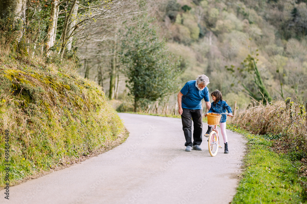Grandfather teaching girl riding bicycle in countryside Grandfather teaching girl riding bicycle in countryside