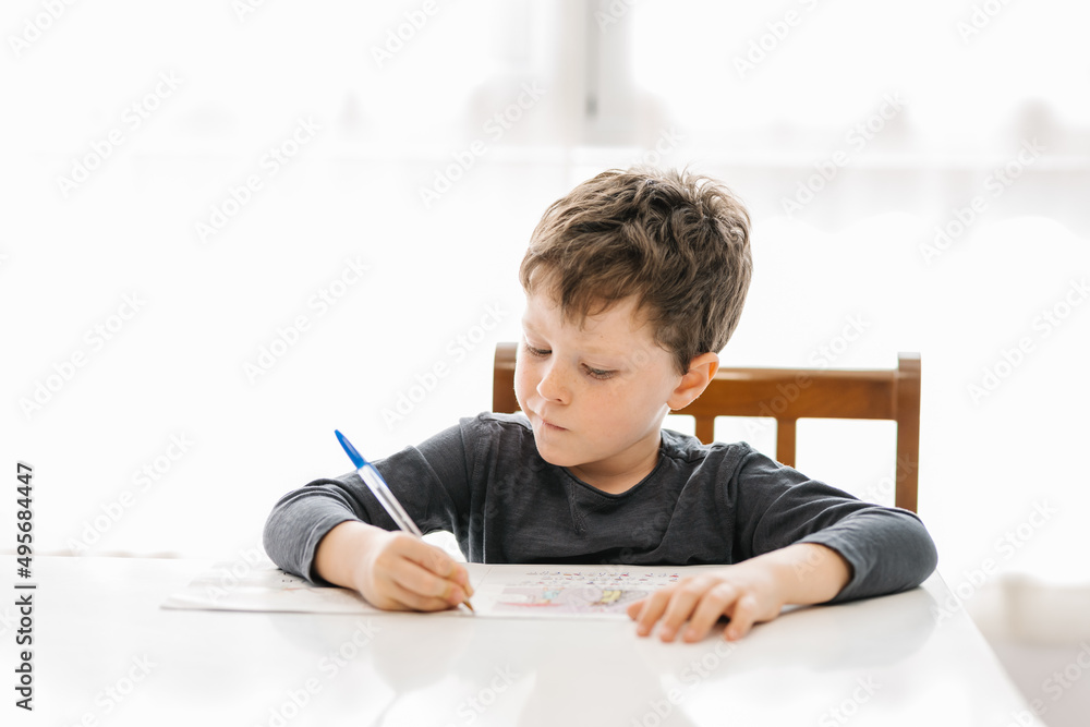 © ADDICTIVE STOCK - Boy writing on paper at table