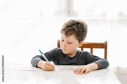 Boy writing on paper at table photo