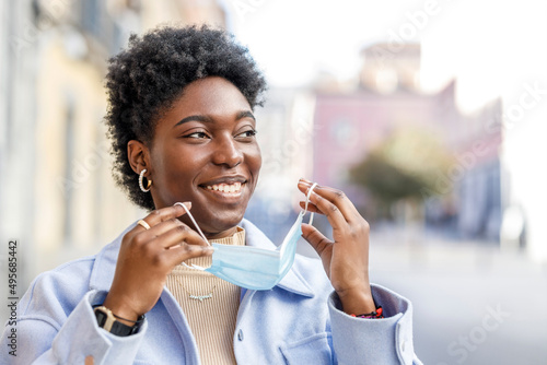 Cheerful black woman putting on medical mask