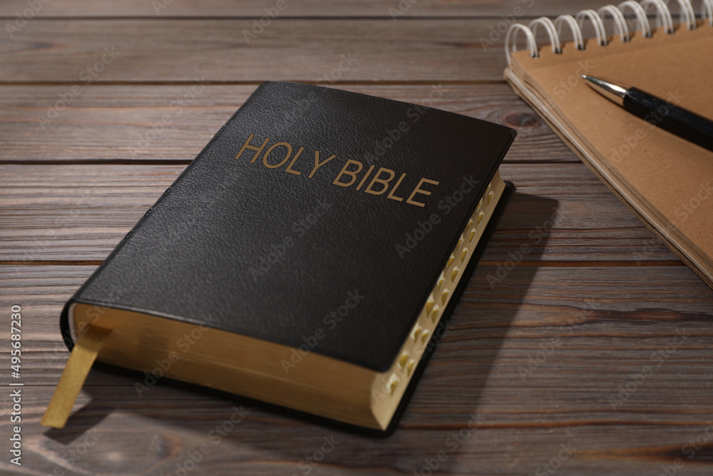 Old hardcover Bible and notebook with pen on wooden table. Religious book Old hardcover Bible and notebook with pen on wooden table. Religious book