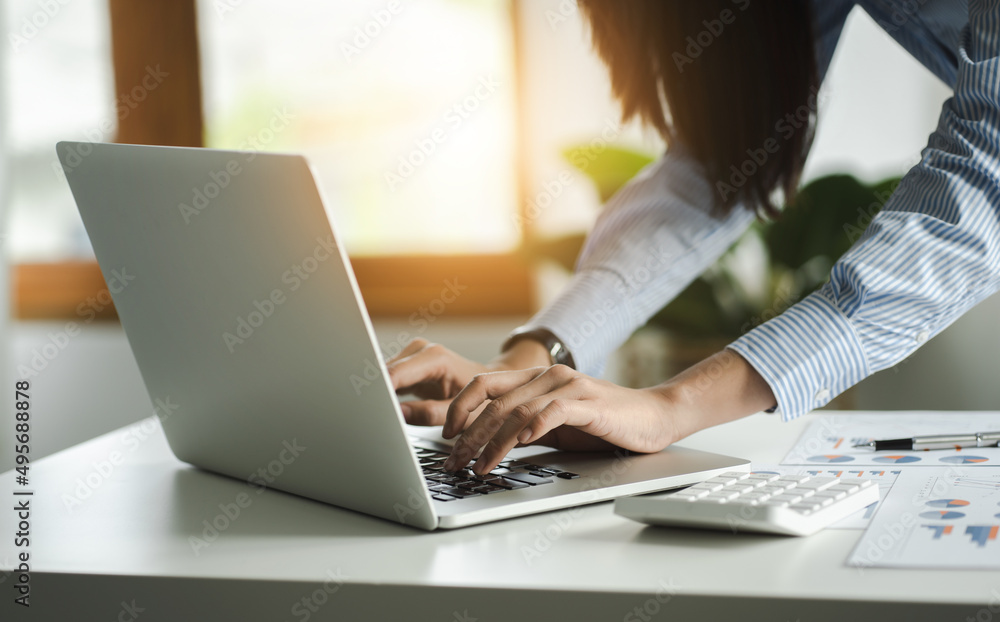 Closeup of business female hands busy typing on a laptop with calculator in office. Closeup of business female hands busy typing on a laptop with calculator in office.