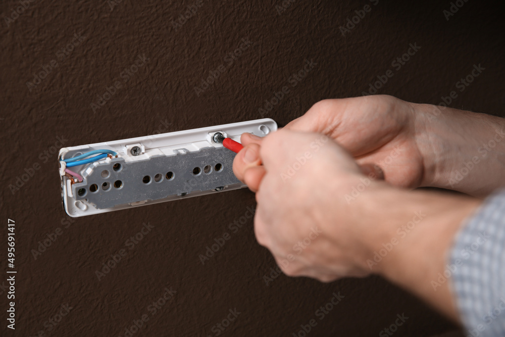 Electrician with screwdriver repairing power socket, closeup Electrician with screwdriver repairing power socket, closeup