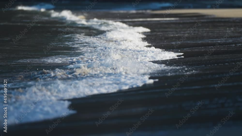 Waves roll slowly on the shallows of the sandy beach in Ersfjord. White foam rising and disappearing. Slow-motion, pan follow. Waves roll slowly on the shallows of the sandy beach in Ersfjord. White foam rising and disappearing. Slow-motion, pan follow.