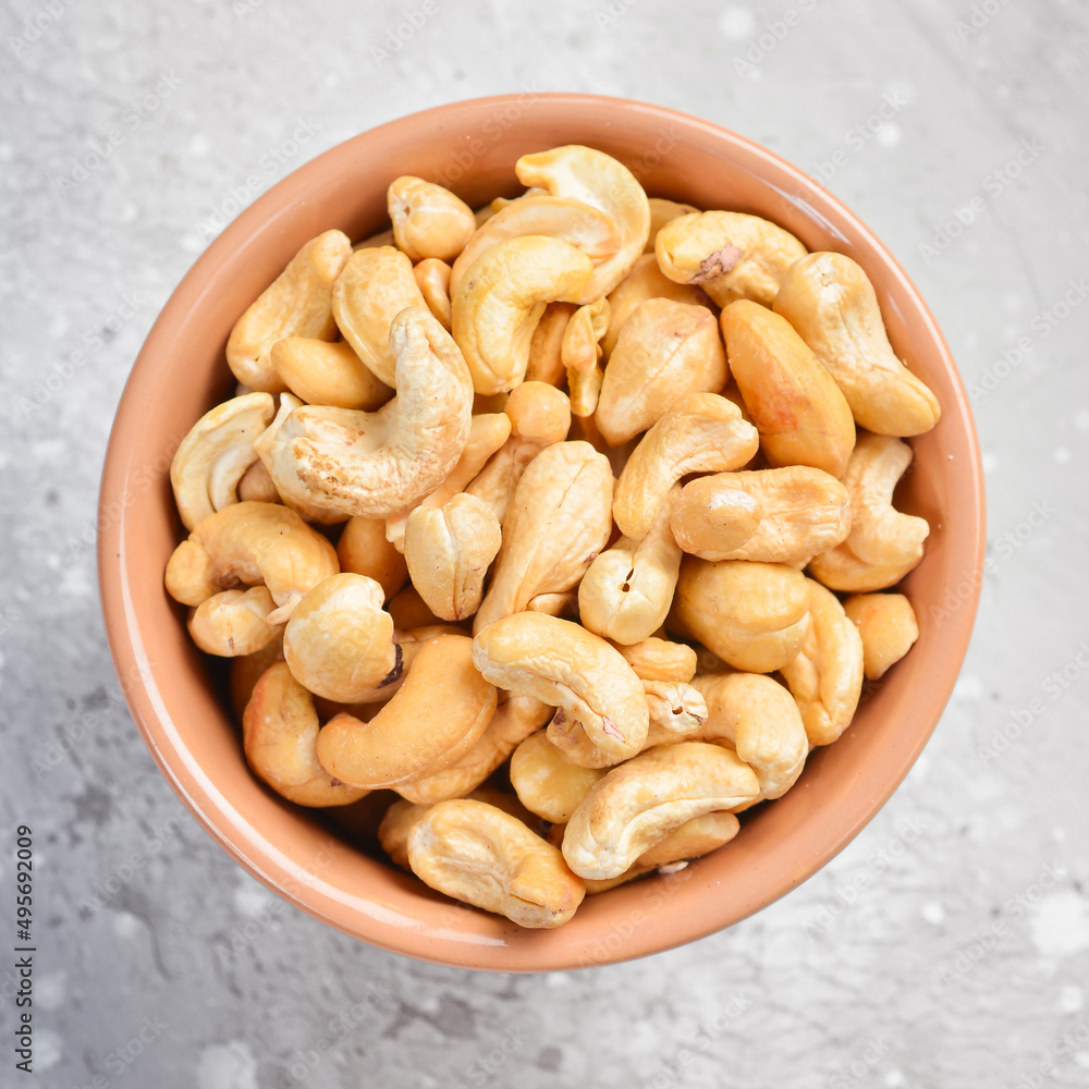 Cashew nuts in a bowl. On a stone background. Top view. Free space for text. Cashew nuts in a bowl. On a stone background. Top view. Free space for text.