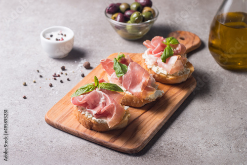 Bruschetta with prosciutto, basil, olives, spices and herbs. Appetizers.