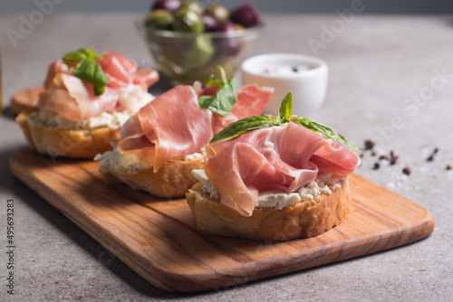 Bruschetta with prosciutto  basil  olives  spices and herbs. Appetizers.