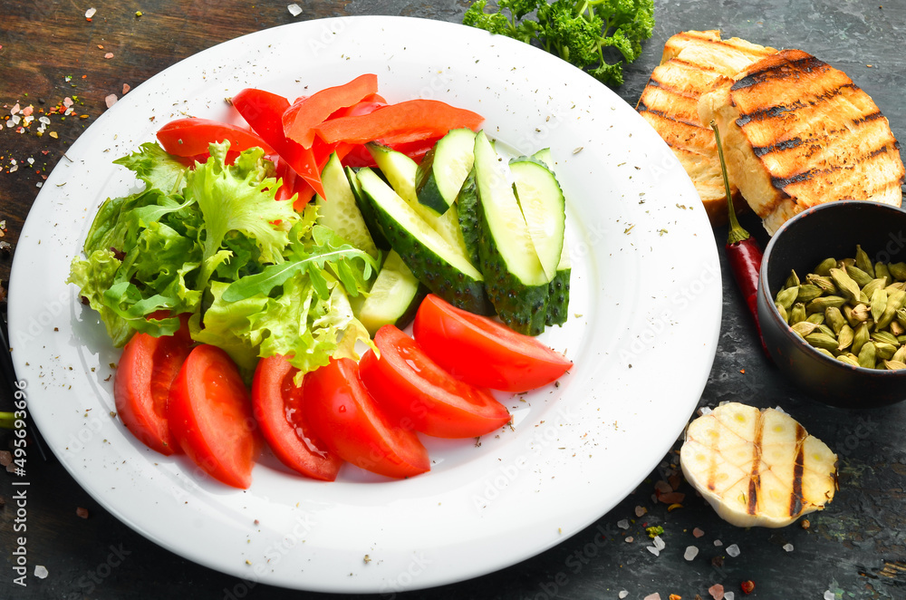 Assorted vegetables in a plate. Slicing fresh vegetables: cucumber, tomato, pepper. Restaurant menu. Top view.