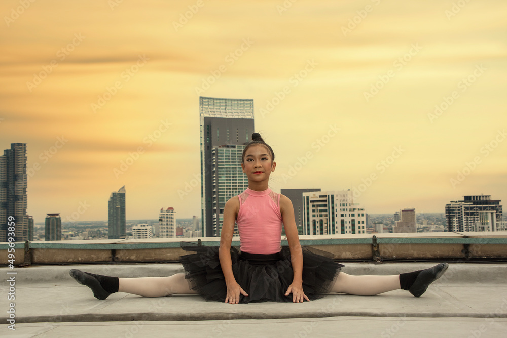 teenage girl in a ballerina dress sits in a tent and rips her legs off a tall building behind the city view. 