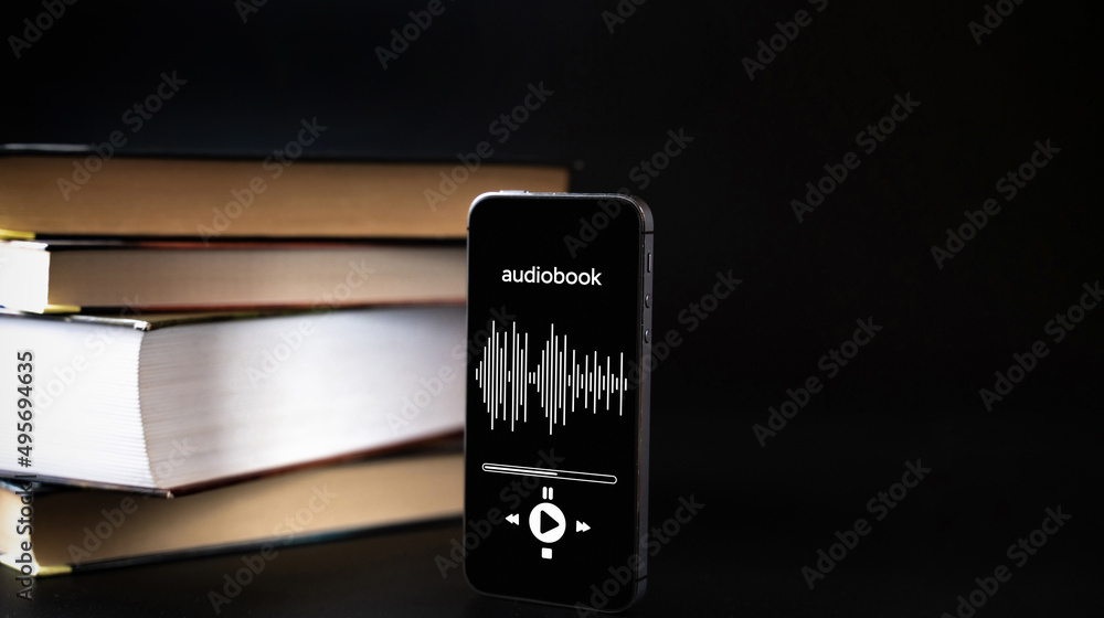 Audio listen book. Phone screen with audiobook app on paper books black background. Online education course, E learning class and e book digital technology concept.