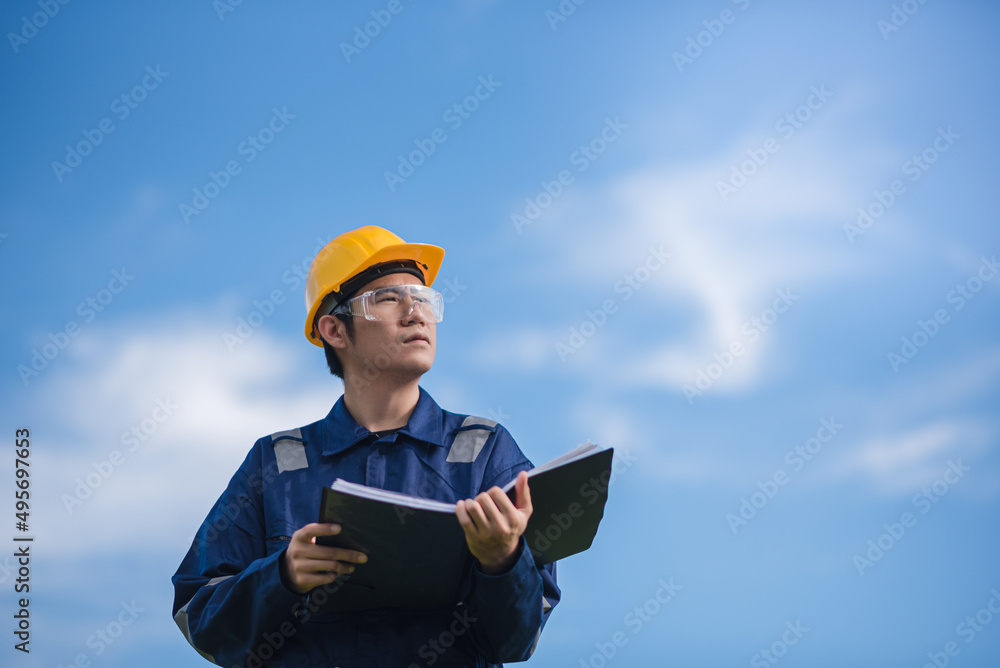 An Engineer is holding a document and looking away. An Engineer is holding a document and looking away.