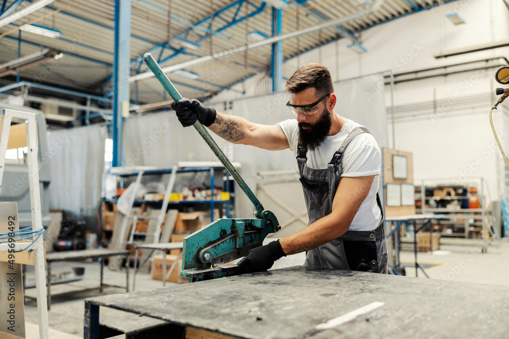 A worker cutting metal parts at workshop.