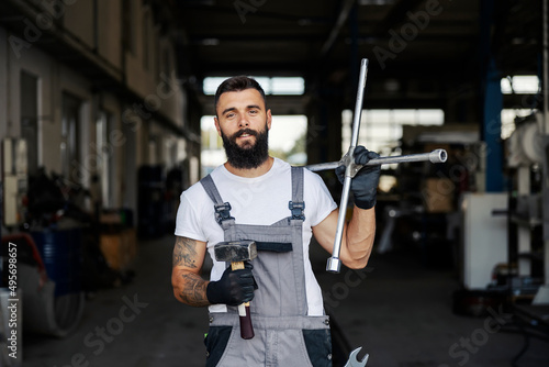 Portrait of an auto mechanic holding tools and smiling at the camera.