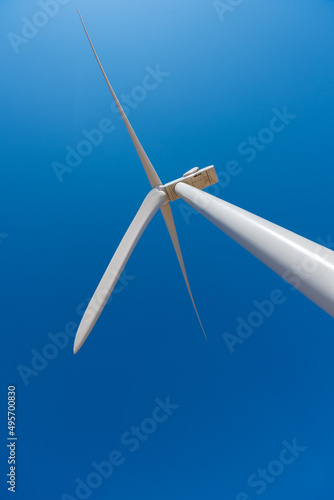 Single wind power turbine fan against a blue sky © Juan Garcia
