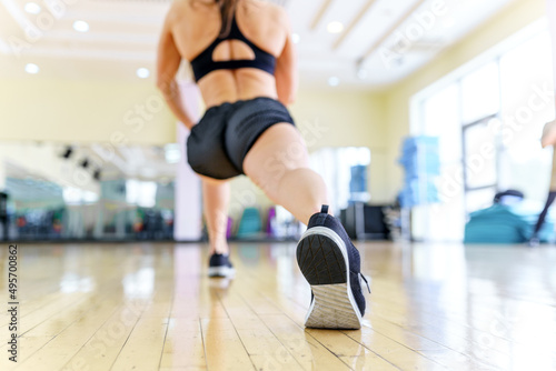 Active lifestyle of a woman. The girl is doing a warm-up in the gym. Fitness instructor with athletic body in sport club. Female bodybuilder doing exercises to stretch muscles