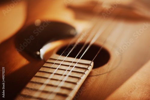 An old vintage acoustic guitar with metal strings is illuminated by sunlight. A musical instrument. Solfeggio.