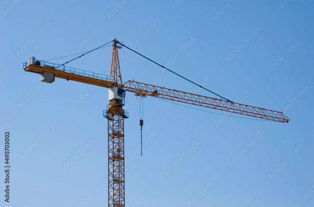 Large construction site cranes working on a building complex with clear blue sky.