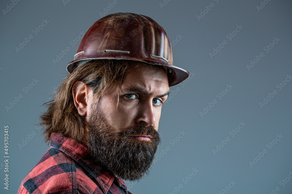 Obraz premium Building, industry - builder concept. Bearded man worker with beard in building helmet or hard hat. Man builders, industry
