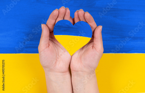 concept of end war in Ukraine. heart hold in hand on colored flag Ukraine