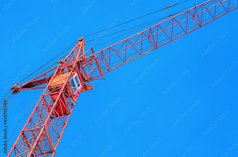 Construction crane on a background of blue sky. Crane driver's cab close up. Construction industry. Construction crane on a background of blue sky. Crane driver's cab close up. Construction industry.