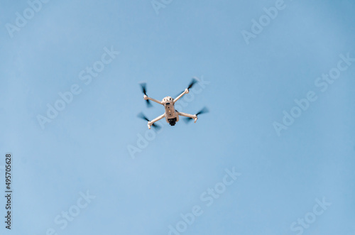 Drone flying in the air. Bottom view. Blue sky background. New technologies.