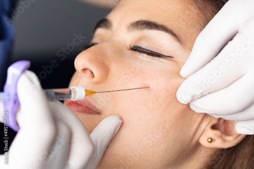 Plastic surgery clinic. Hands of cosmetologist making injection holding syringe. Concept of healthy face, skin care, middle age skin care cosmetics, aesthetics. 