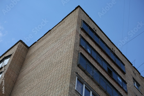Brown brick house. A corner of a Soviet high-rise building, taken from below against a blue background