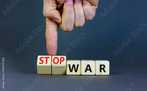 Stop war symbol. Businessman turns cubes and changes concept words War to Stop war. Beautiful grey table grey background. Business and stop war concept. Copy space.