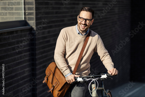 A laughing man pushing bicycle while walking outdoors.