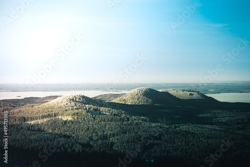 Bird's eye view of snowy hills covered with forests in winter on a sunny day photo