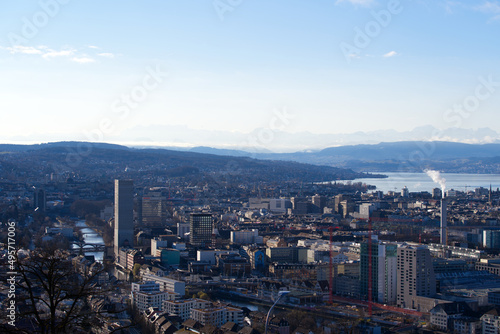 Aerial view over City of Zürich with Lake Zürich and Swiss Alps in the background on a blue and cloudy spring morning. Photo taken March 14th, 2022, Zurich, Switzerland. © Michael Derrer Fuchs