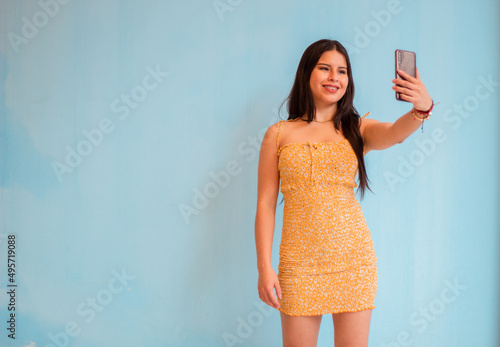 Foto de una dama , sostenga el teléfono, lea los comentarios positivos de la publicación del blog, use una camiseta sin mangas blanca casual, una falda corta amarillo aislada con un fondo de color ama