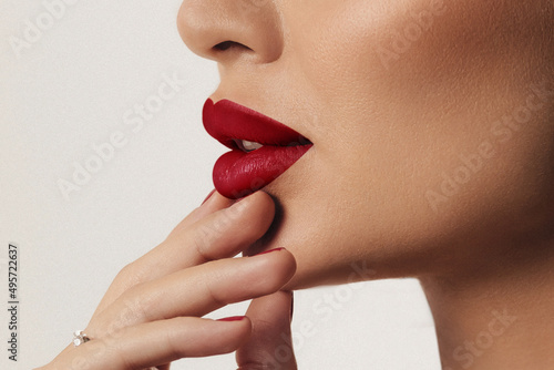 Close up side view of beautiful woman's lips with red lipstick and perfect shiny skin. Cosmetology, pharmacy or fashion makeup concept. Filmed in a beauty studio. A passionate kiss