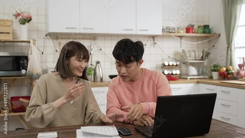 happy Asian young couple planning family finance together at home. the man smiling with clenched fist and clapping hand with his wife cheering for successful investment