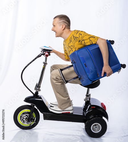 guy in an electric car. a man in the studio on a tricycle with a suitcase. travel white background. electric scooter. ecological transport