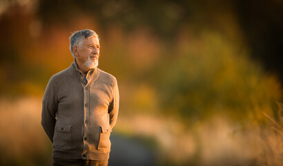 Portrait of handsome senior man in the autumn outdoors. Active senioor enjoying his retirement in the  nature