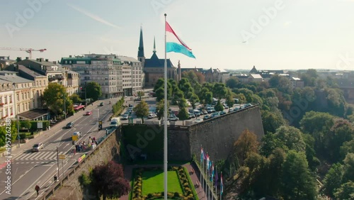 Establishing Aerial shot of Luxembourg Cityscape Panorama with Landmark Skyline and National Flag Waving on Wind. Tourism, Travel or Urban b-roll Background. 4K drone zoom in shot photo