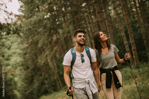 Couple of hikers with backpacks walk through the forest