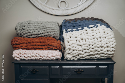 Closeup shot of soft custom made chunky blankets on the wooden small table in the house