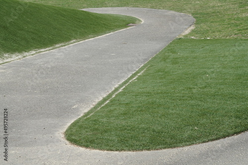 Serpentine aus Asphalt, Weg in einem Park mit Gras und Straßenbelag