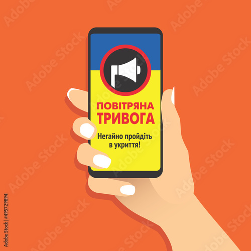 Female hand hold smartphone with air raid alert message in Ukrainian language. Woman showing cell phone with air-raid warning. Government of Ukraine informs about the danger. Vector EPS8 illustration. photo