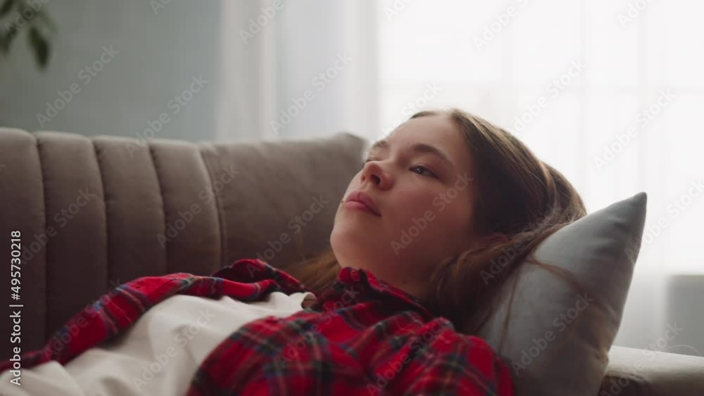 Teenage girl in casual clothes falls down on comfortable grey sofa closeup slow motion. Tired brunette student rests after test. Domestic life and leisure Teenage girl in casual clothes falls down on comfortable grey sofa closeup slow motion. Tired brunette student rests after test. Domestic life and leisure