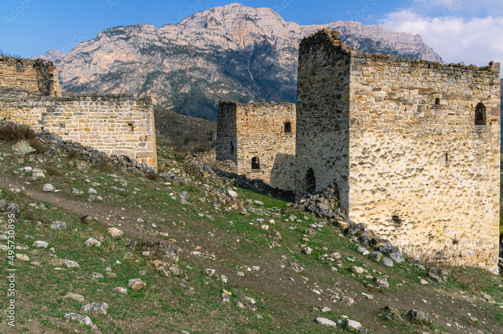 An abandoned medieval town. Military and residential ancient towers built of stones. Landscape in the mountains with a view of the ruins.
