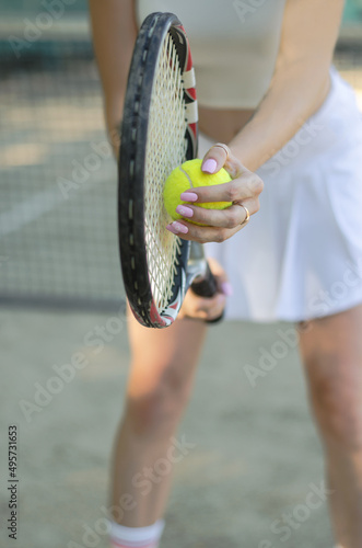 Unrecognizable woman holding tennis racket and ball in her hands