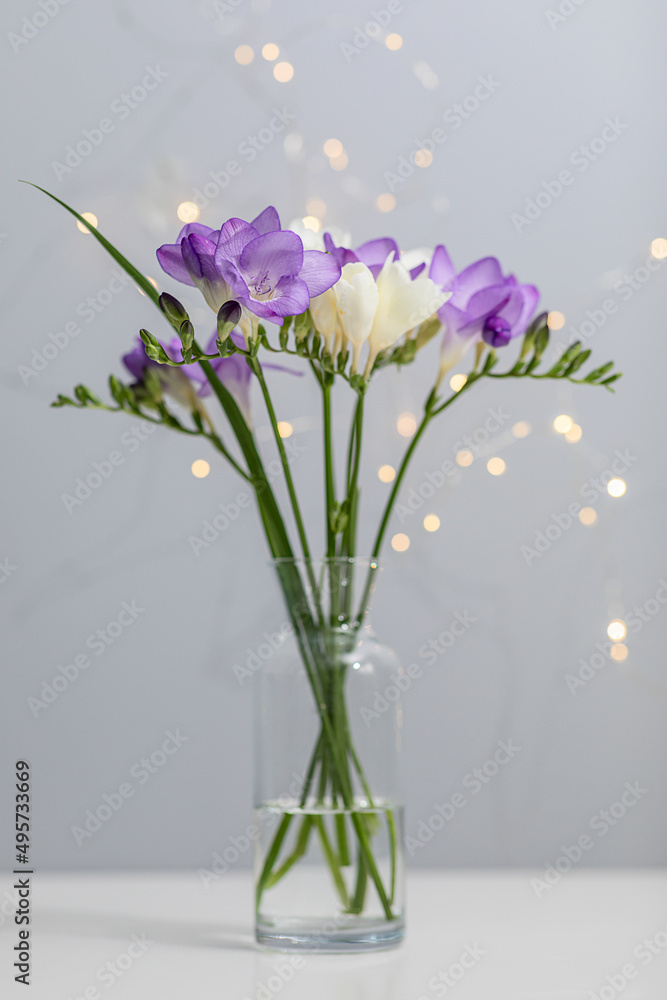 bouquet of twigs of delicate purple and white freesia flower in a glass bottle on a gray background bouquet of twigs of delicate purple and white freesia flower in a glass bottle on a gray background