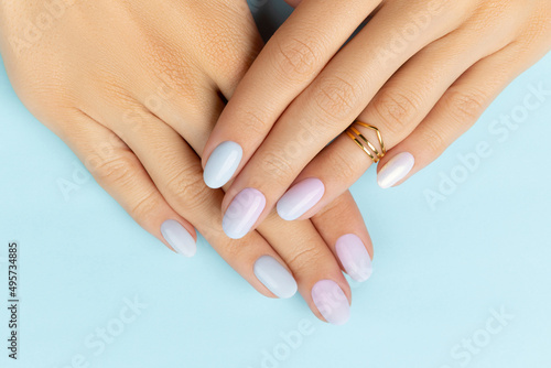Womans hands with trendy manicure on blue background. Summer nail design photo